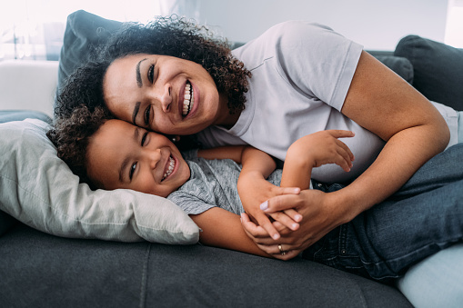 Shot of a mother and her little boy spending time together at home. Happy single mother and son having fun in the living room. Portrait of mother embracing her son on the sofa.