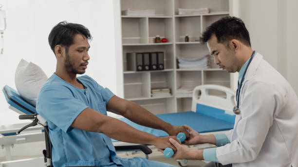istock Physical therapist helping a patient while stretching his legs on a bed in a clinic or hospital. Young man attends a physiotherapy course on muscle weakness pain. and heel pain with elastic 2148664391