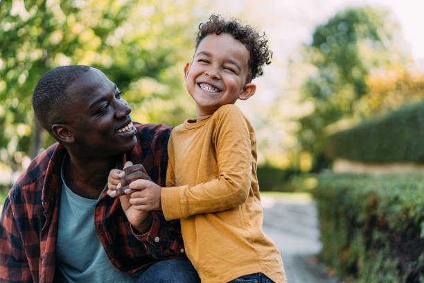 Father and son hugging each other while playing outdoors.