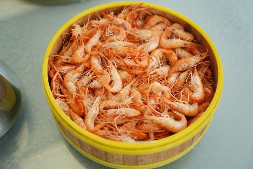 Boiled crayfish and shrimps with green salad and lemon slices on a plate, blue wooden background, top view