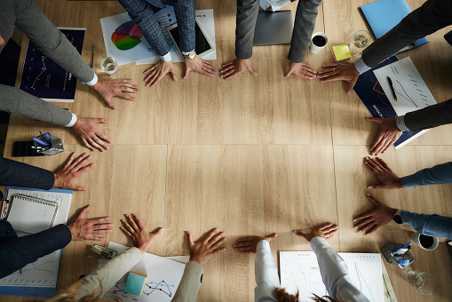 High angle view of unrecognizable business team making a circle of their hands on a meeting in the office. Copy space.