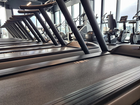 A linear arrangement of treadmills in a gym, showing exercise equipment ready for use