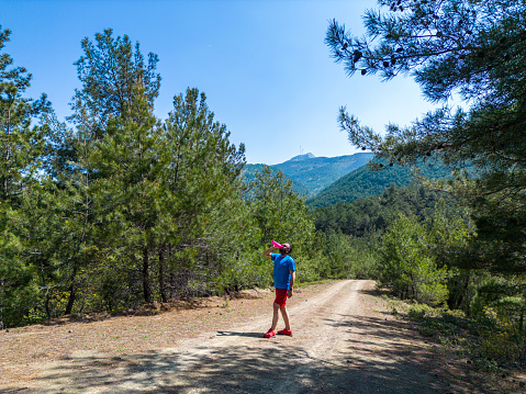 Young man trail running  along mountain road between trees