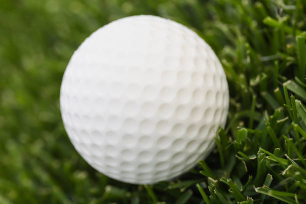 The golf ball is on a green lawn in a beautiful golf course with morning sunshine. Ready for golf in the first short. Sports that people around the world play during the holidays for health.