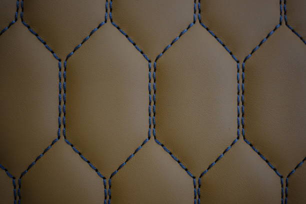 Blue contrast thread on a brown leather car seat close-up
