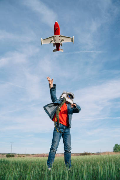 Adorable kid wearing a helmet and playing alone with a space shuttle at field