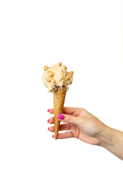 istock Hazelnut Ice cream cone with female hand on white background 2148672311