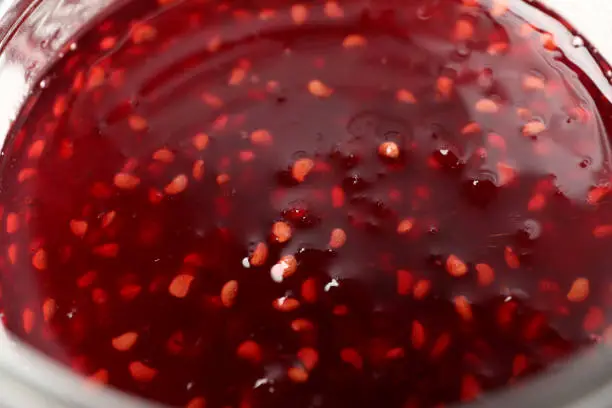 Photo of Jar of raspberry jam all over background, close up
