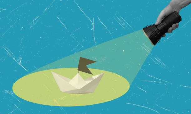 istock Contemporary art collage depicting a hand holding a flashlight and shining on a paper ship. 2148672772