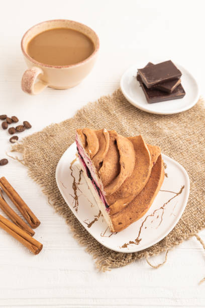 Zephyr or marshmallow cake with cup of coffee on white wooden background and linen textile. side view, close up.