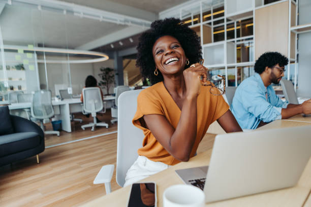 mujer de negocios feliz sentada en una oficina de inicio y trabajando en una computadora portátil - coworking fotografías e imágenes de stock