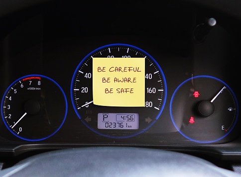 Note stick on car console with text written BE CAREFUL BE AWARE BE SAFE ,behind steering wheel , to remind driver to drive carefully