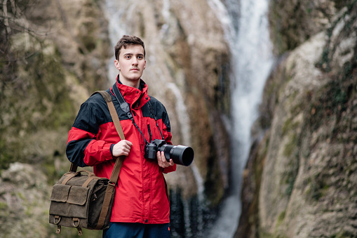 Portrait of a young photographer near a waterfall