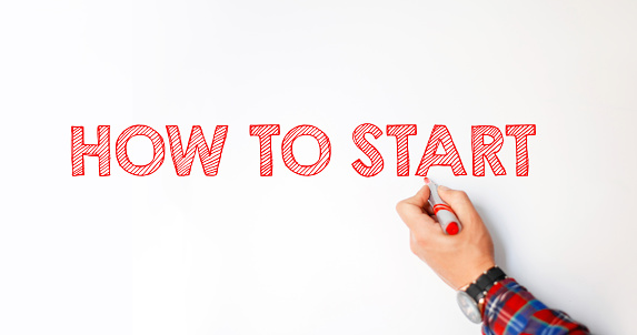 Business coach man writes on the whiteboard the text: How to start. Creative idea and motivation