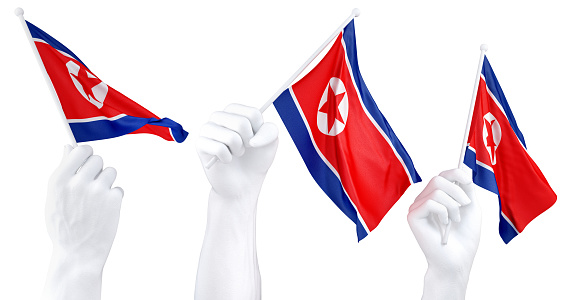 Three isolated hands waving North Korea flags, symbolizing national pride and unity
