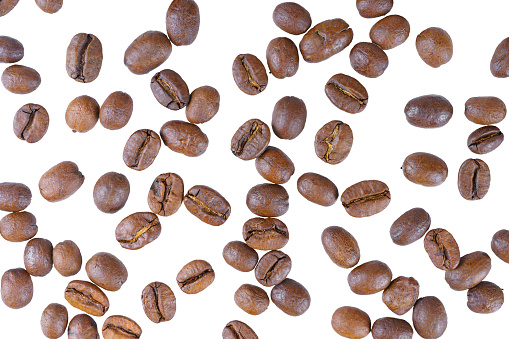 Scattering of aromatic roasted arabica coffee beans close up, macro isolated on white background. Wallpaper, texture, background, top view.