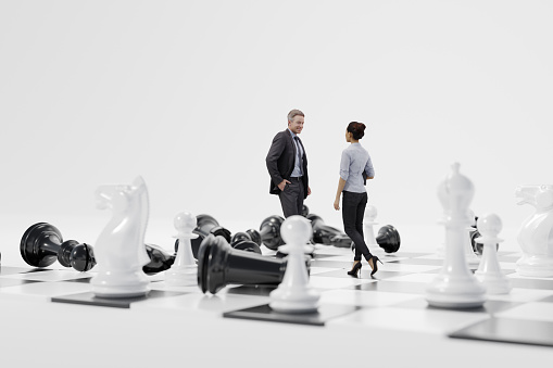 Checkmate. Businesswoman stands against a businessman on the chessboard surrounded by a chess pieces. All black chess pieces around the businessman a laying on the chess board.