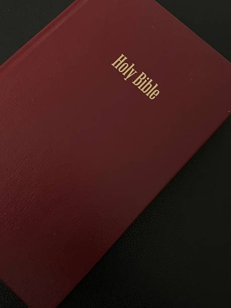 istock Bible in burgundy cover on a black background 2148676738