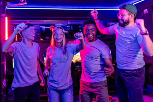 A jubilant scene capturing a group of standing gamers, including teenagers and young adults of various ethnicities, cheering enthusiastically for a triumphant win in an eSports competition, embodying the spirit of shared success and excitement