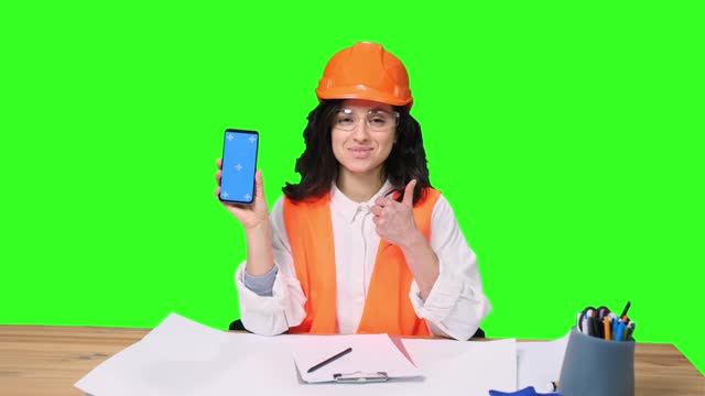 Female architect showing phone screen and thumbs up on the chroma key