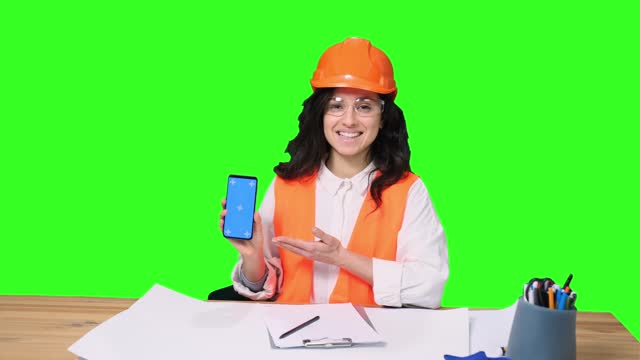 Happy female architect holding mobile phone with copy space on the chroma key
