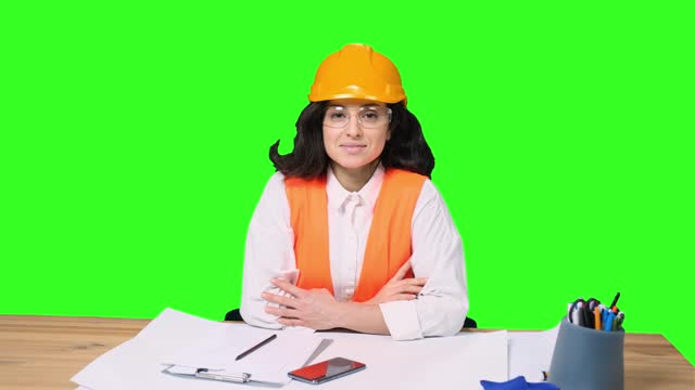 Happy female architect in protective helmet looking at camera on the chroma key