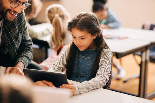 istock Teacher shows a student how to use a digital tablet in an elementary school 2148679754