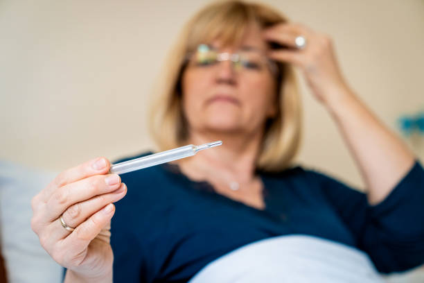 Caucasian illness woman measuring temperature sitting on the sofa at home.