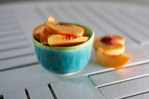 Two halves of a xoconostle fruit showcasing its vibrant pink interior and seeds, resting on a bamboo cutting board alongside a knife