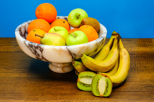 Exotic and tropical fruits in a marble bowl against a blue background and shot in the studio