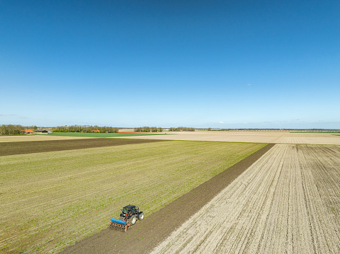 Tractor cultivating the soil during springtime seen from above during a sunny and dry springtime day. Aerial view drone view from directly above.