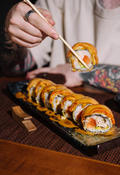 istock Person holding sushi roll with chopsticks 2148682679
