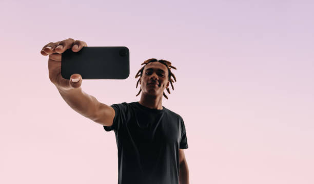 istock Gen Z man taking a selfie with a smartphone on a pink studio background 2148683066
