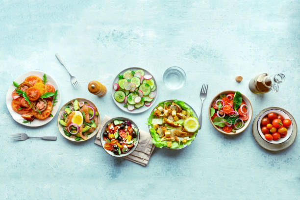 Fresh salads, overhead flat lay shot of an assortment. Variety of plates Fresh salads, overhead flat lay shot of an assortment. Variety of plates and bowls with green vegetables. Healthy food, top shot, with copy space restaurant table layout stock pictures, royalty-free photos & images