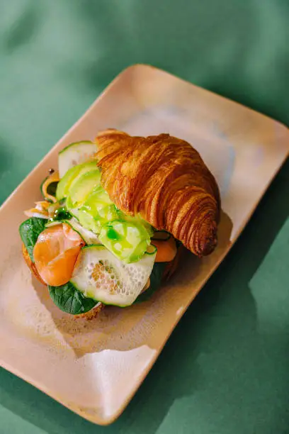 Artisan croissant sandwich with smoked salmon and fresh vegetables, elegantly plated