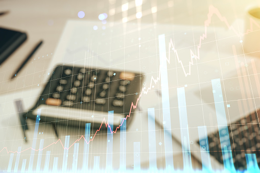 Abstract virtual financial graph hologram on blurry calculator and computer background, financial and trading concept. Multiexposure