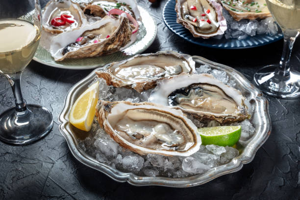 istock Oysters on ice, with various toppings and white wine, on black 2148685684