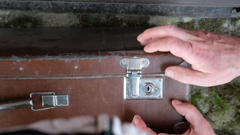 Old suitcase lock. Key lock. The person's hands close the suitcase.