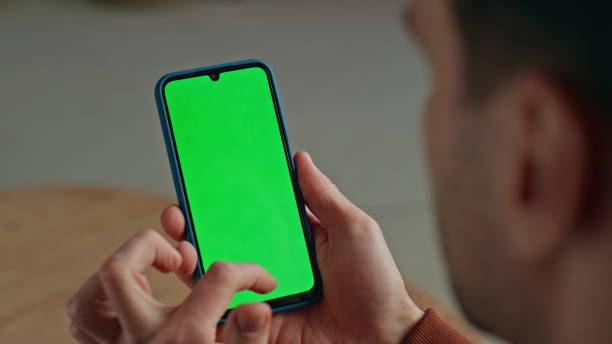 istock Unrecognizable man scrolling smartphone with green screen on workplace closeup 2148686442