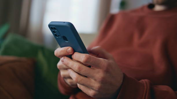 istock Man hands texting smartphone relaxing at couch close up. Freelancer messaging 2148687068