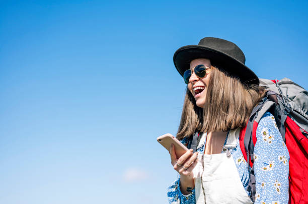 istock Woman with red backpack and hat using a smart phone 2148687684