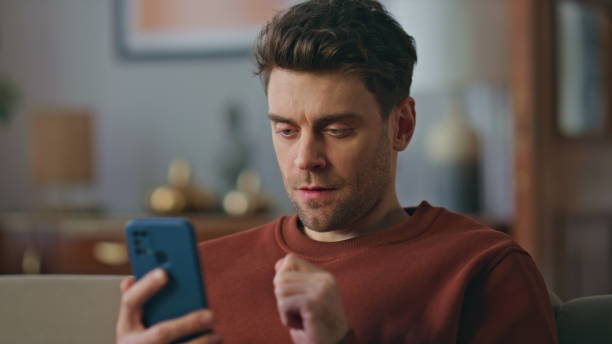 istock Portrait guy opening smartphone bank application sitting couch. Smiling man 2148688348