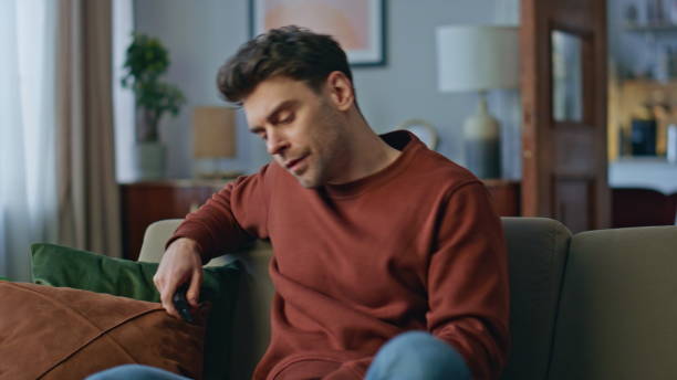 istock Tired man choosing channel relaxing home sofa after hard day close up. Bored guy 2148688948