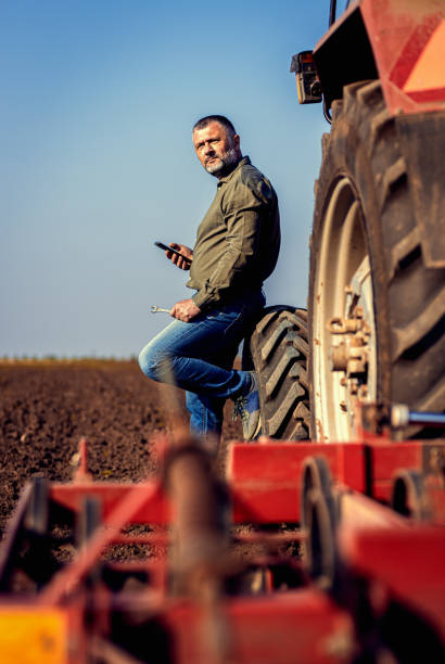 istock Farmer using tablet while resting after cultivation of soil leaning on tractor tire. 2148689156