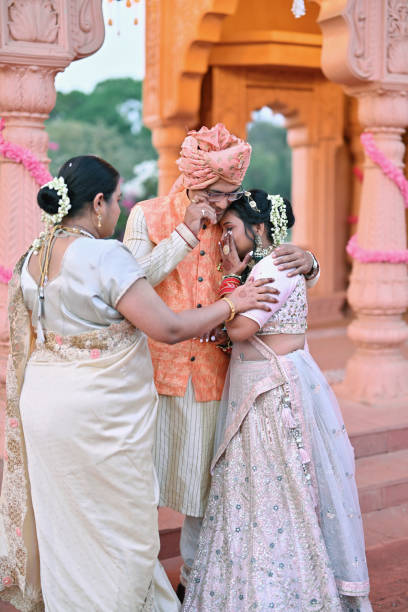 Emotional moment of Bride with her father as she is set to start her new life in the backdrop of a beautiful palace In this emotional moment, the bride shares a heartfelt embrace with her father, her eyes shimmering with tears of love and gratitude as she prepares to embark on her new life. Her father, visibly moved, hold her close, he couldn't control his feelings of sadness at the thought of letting their daughter go. This tender exchange is filled with the bittersweet emotions of letting go and moving forward, underscored by the unbreakable bond of family love. bride hugging father on wedding day stock pictures, royalty-free photos & images