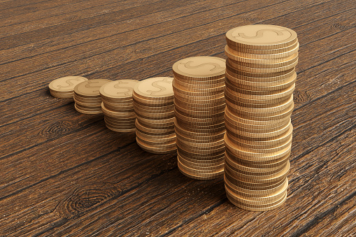 Stacks of gold coins forming a growing bar charts on a wooden table. Illustration of the concept of finance, investment, economy and central bank monetary policies