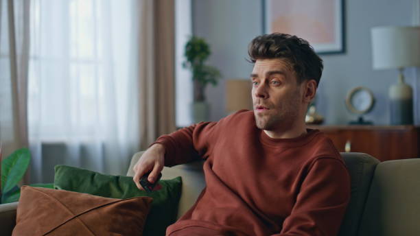 istock Dissatisfied guy watching television at couch close up. Bored brunet switching 2148689784