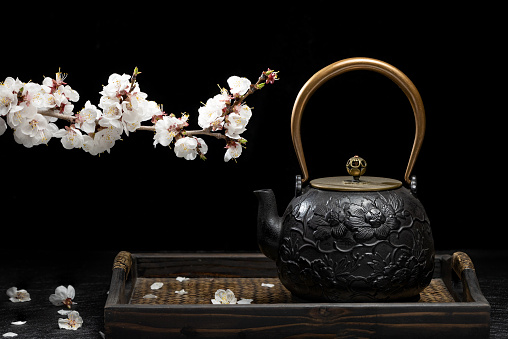 Apricot flowers and teapots on a black background