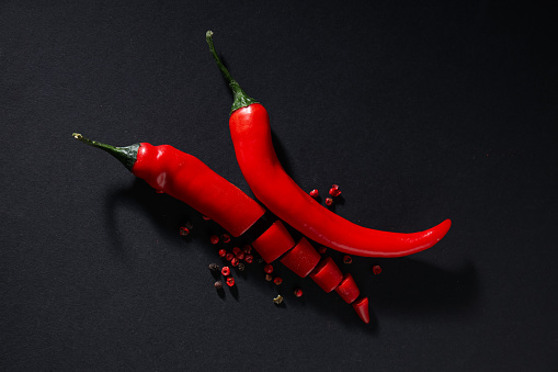 Close up view of ripe red chili peppers making a flame shape on rustic brown background. Low key DSRL studio photo taken with Canon EOS 5D Mk II and Canon EF 100mm f/2.8L Macro IS USM.