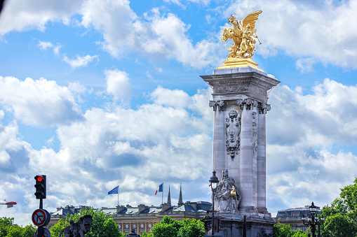 Golden sculpture on concrete column, ornament on Alexandre III bridge under the cloudy blue sky in Paris, France